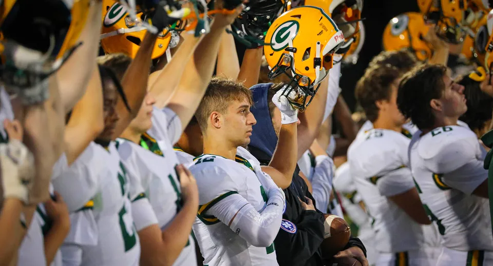 I giocatori di football americano della Bishop Guertin High School tengono in alto i loro caschi gialli.