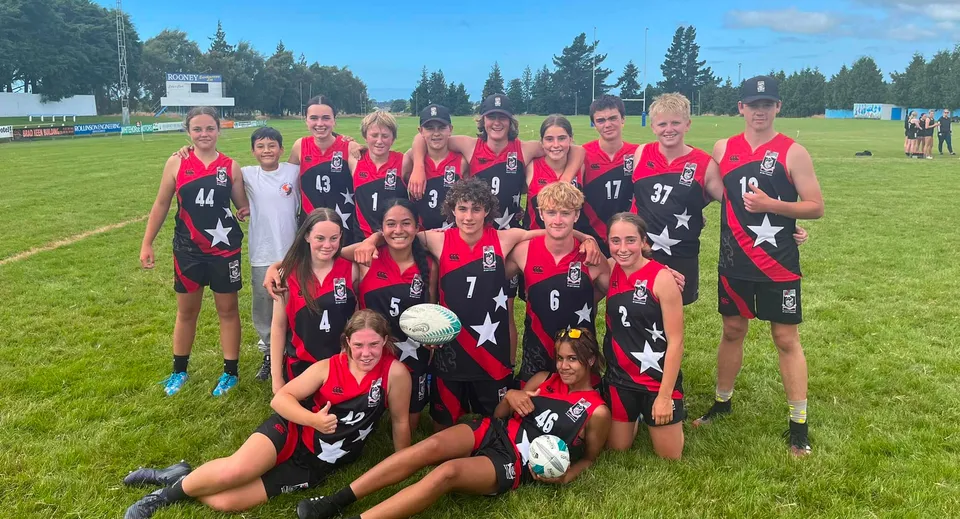 Un gruppo di calciatrici in maglia rossa e nera si trova su un campo da gioco nel campus del Mount Hutt College.