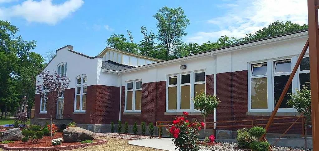 El moderno edificio de ladrillo y pintado de blanco de la Northern Academy con grandes ventanas y un patio delantero ajardinado bajo un cielo azul.