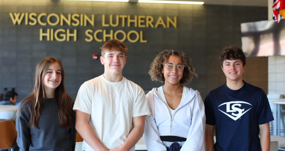 Quattro studenti sono in piedi davanti all'insegna della Wisconsin Lutheran High School.