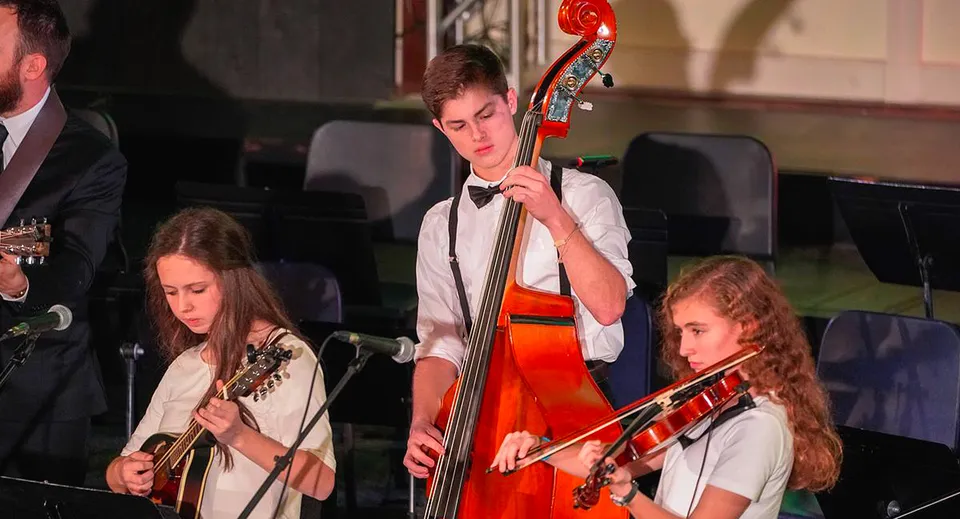 Un gruppo di musicisti suona sul palco della Ben Lippen School in una sala buia.