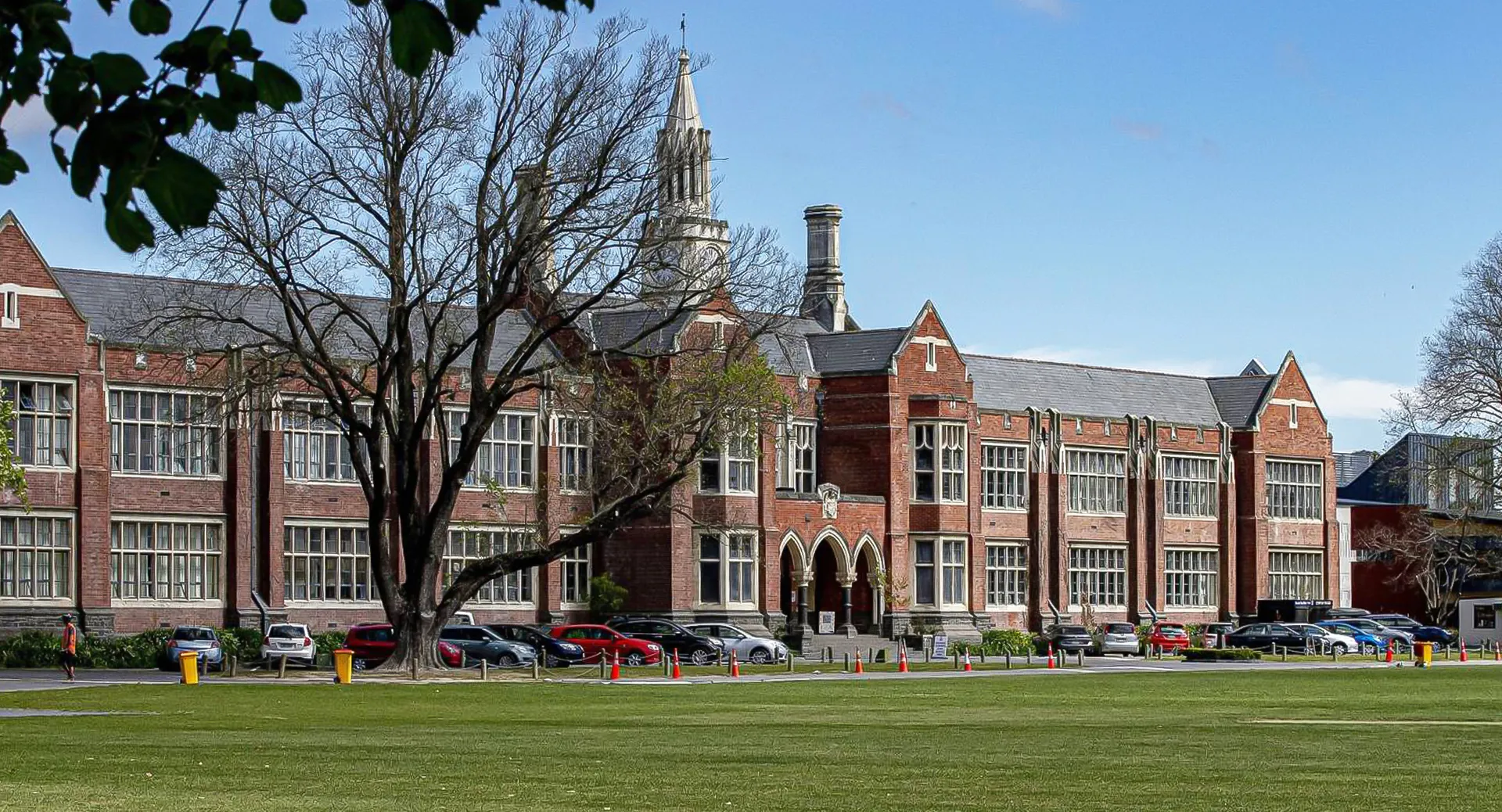 Un grande edificio decorato in mattoni con un'alta torre si erge nel campus della Christchurch Boys High School.