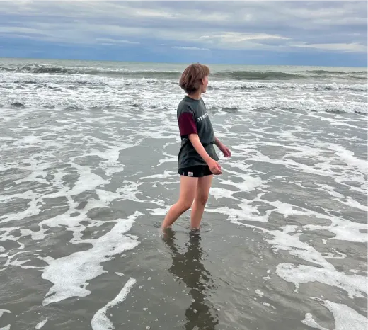 Louisa steht in der Brandung und blickt aufs Meer in Neuseeland