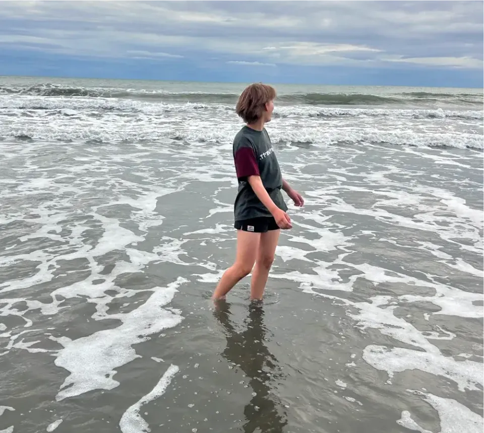 Louisa steht in der Brandung und blickt aufs Meer in Neuseeland