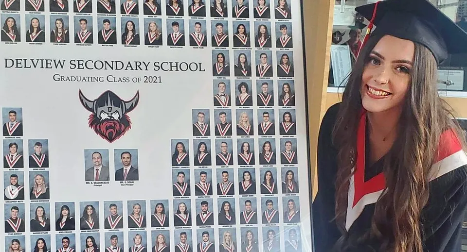 Un gruppo di diplomate e diplomati della North Delta Secondary School del 2021 con una giovane donna in primo piano in abito da diploma.