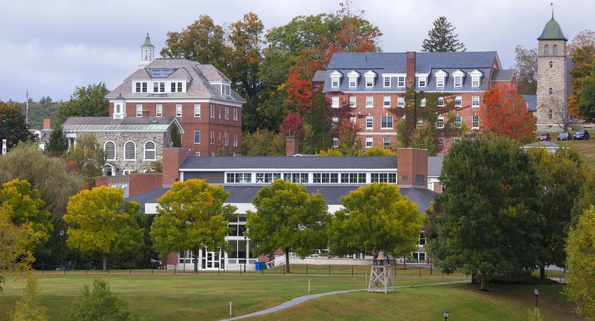 Il campus della Kimball Union Academy mostra edifici storici e moderni circondati da foglie autunnali colorate sotto un cielo nuvoloso.