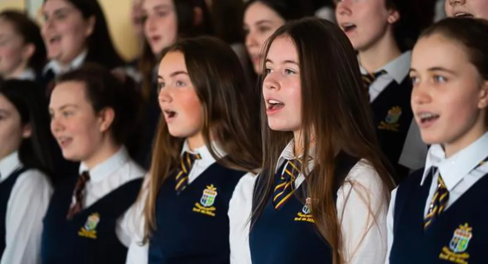 Un gruppo di studenti e studentesse della St. Mary’s Secondary canta insieme nel coro indossando la divisa scolastica.