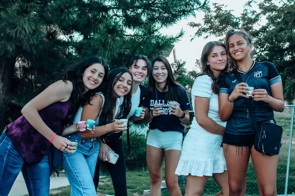 Un gruppo di studentesse sorridenti si trova insieme nell'area verde esterna della Layton Christian Academy.