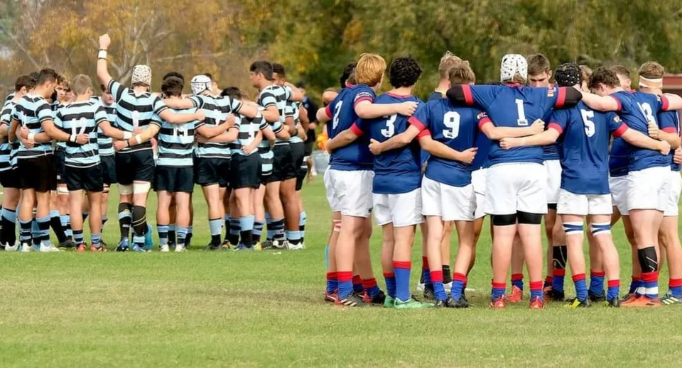 Due squadre di rugby formano un huddle sul campo da gioco del St. Kevin’s College.