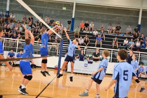 Un equipo de voleibol de la Brisbane Grammar School juega un partido en la cancha ante espectadores.