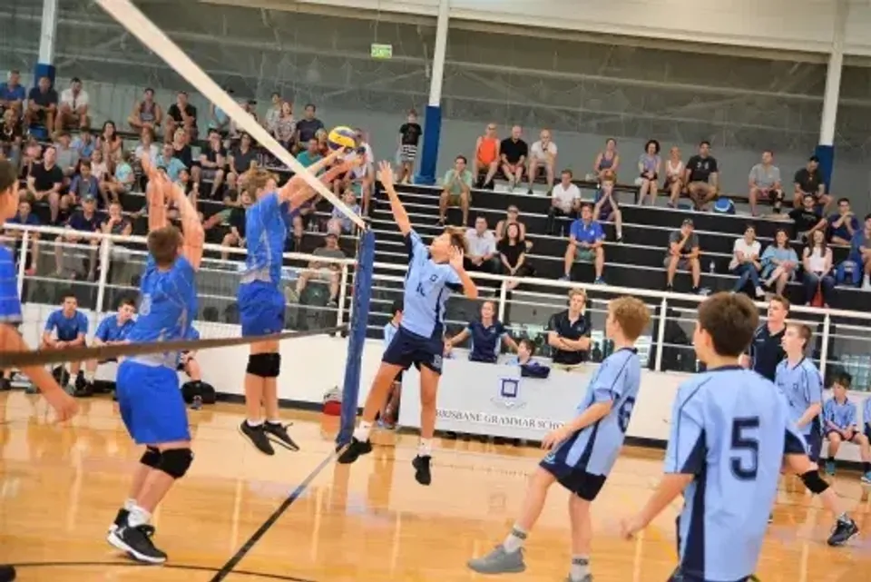 Un gruppo di giocatori di pallavolo della Brisbane Grammar School disputa una partita sul campo davanti agli spettatori.