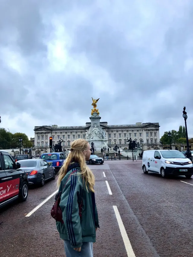 Studentessa osserva Buckingham Palace da una strada trafficata di Londra
