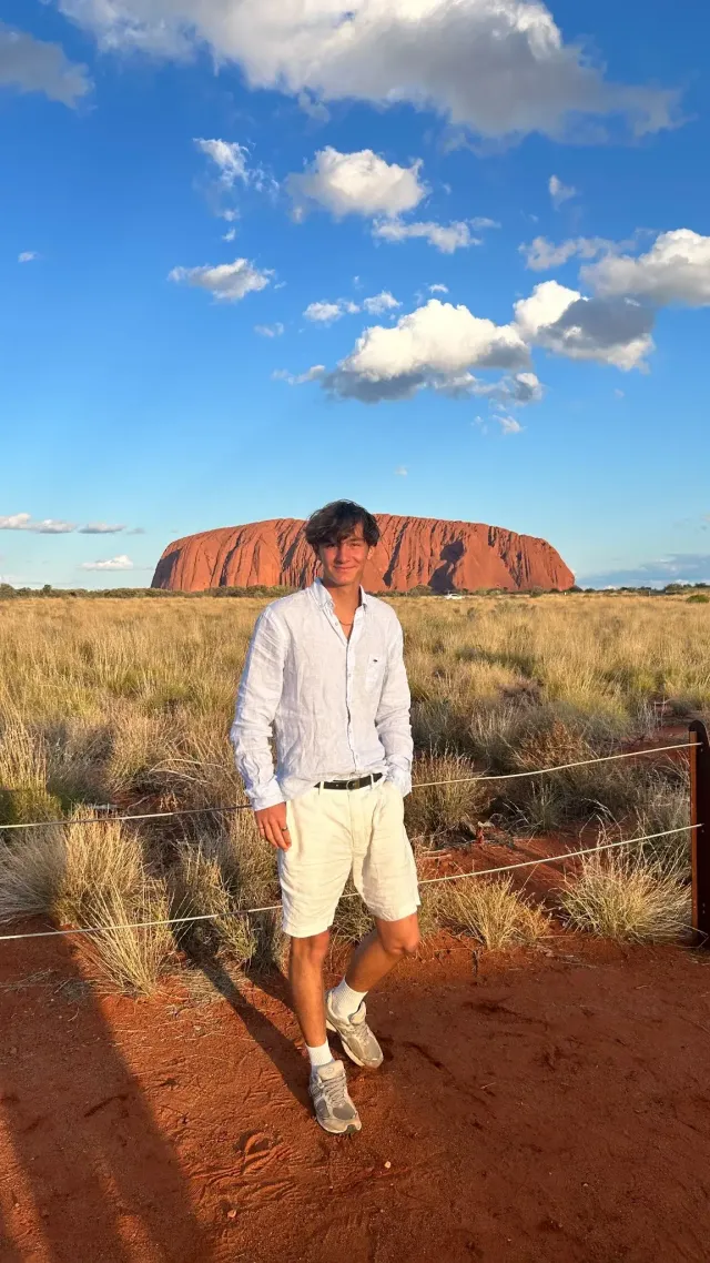 Studente sorridente davanti a Uluru nell'entroterra australiano