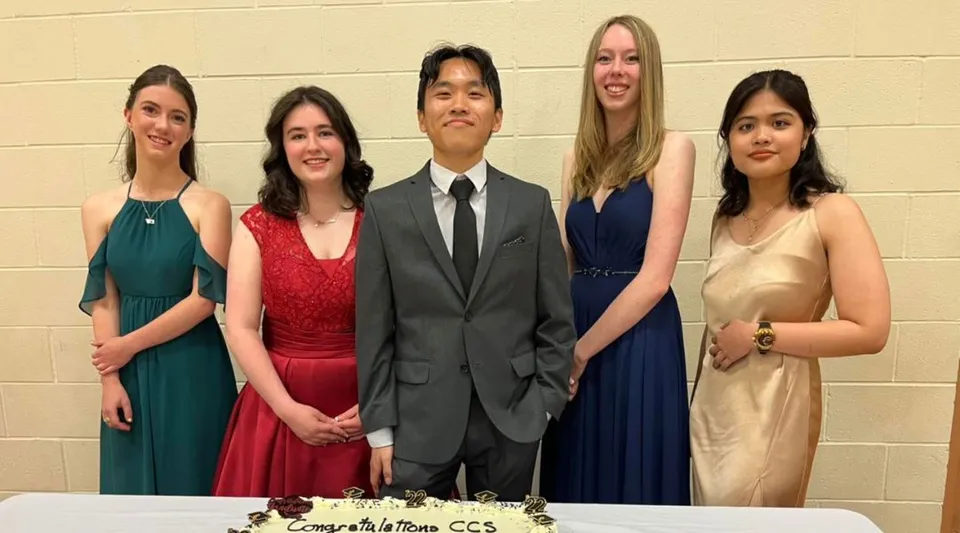 Un gruppo di cinque persone in abbigliamento formale posa davanti a una parete nel campus della Calgary Christian School.