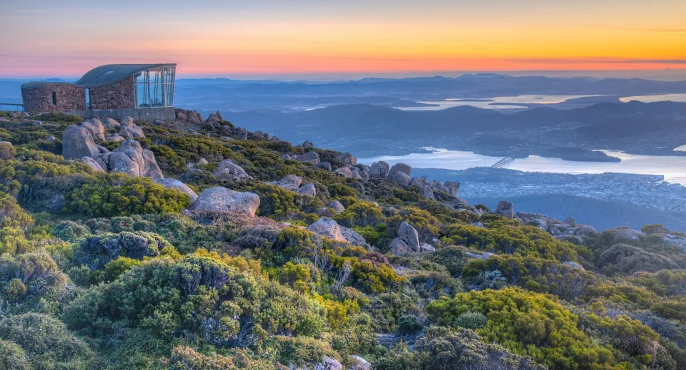 L'edificio in vetro su una roccia offre una vista su montagne e laghi nel campus del Hobart College al tramonto.