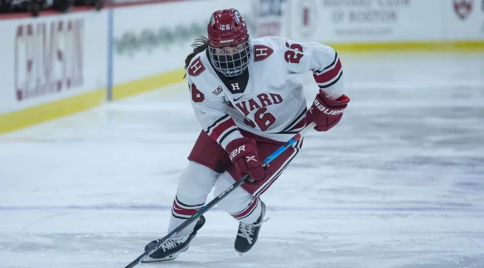 Un giocatore di hockey su ghiaccio della Ontario Hockey Academy in divisa bianca pattina sulla pista da ghiaccio nel palazzetto dello sport.