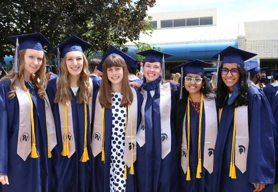 Un gruppo di giovani donne in abito da diploma si trova davanti a un edificio universitario nel campus della Pleasant Valley Secondary School.