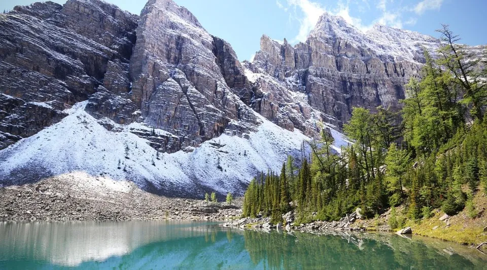 Un lago turchese con montagne innevate e alberi sempreverdi in primo piano vicino alla County Central High School.