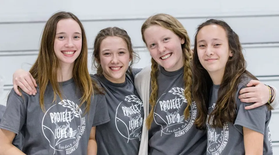 Quattro studentesse della Algoma Christian High School sono in piedi insieme davanti a uno sfondo neutro e sorridono.