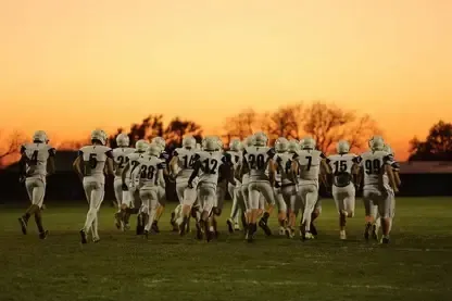 Figuras humanoides futuristas marchan por un campo de césped al atardecer en los terrenos de Nebraska Christian Schools.