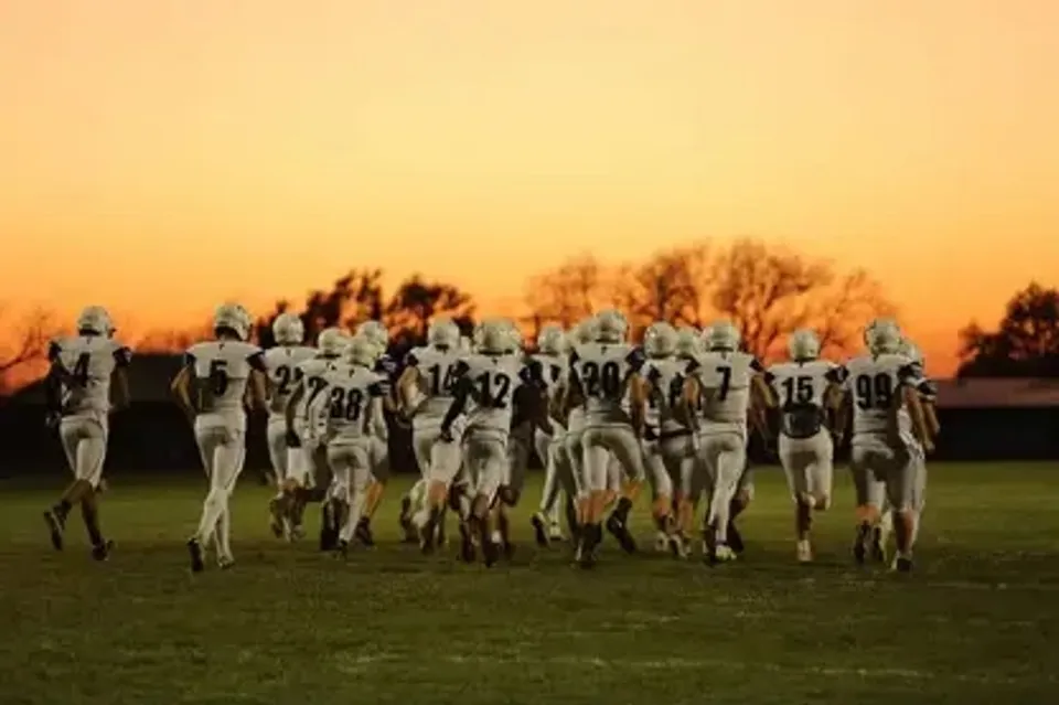 Figure umanoidi futuristiche marciano su un campo erboso al tramonto nel campus della Nebraska Christian Schools.
