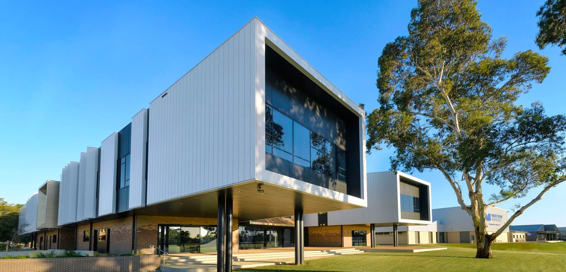 L'edificio moderno della Murray Bridge High School con grandi vetrate si trova in un contesto simile a un parco con alberi e prati.