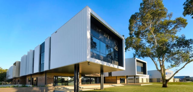 L'edificio moderno della Murray Bridge High School con grandi vetrate si trova in un contesto simile a un parco con alberi e prati.