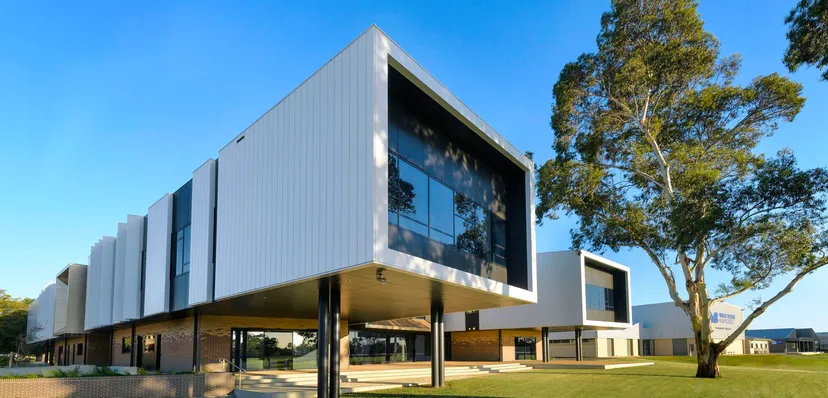 L'edificio moderno della Murray Bridge High School con grandi vetrate si trova in un contesto simile a un parco con alberi e prati.