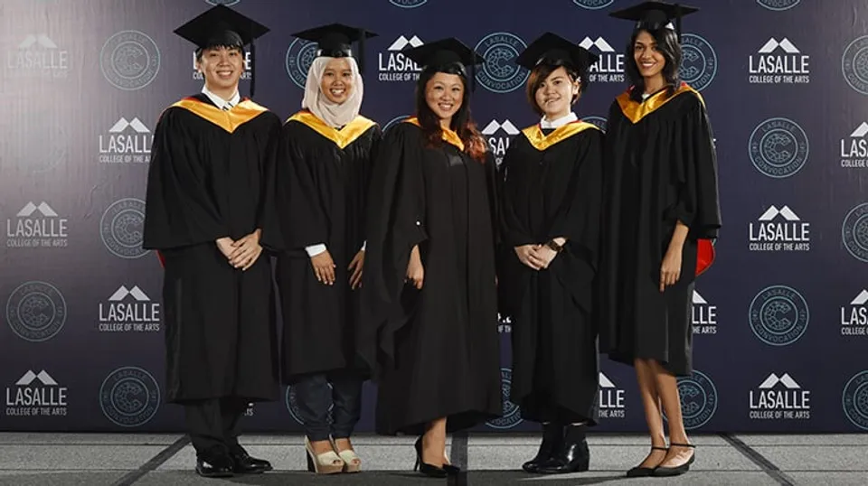 Un gruppo di diplomati in abito accademico posa davanti a uno sfondo con il logo del LaSalle College Vancouver.
