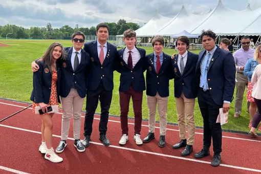 Siete jóvenes vestidos con chaqueta y corbata posan en una pista de atletismo