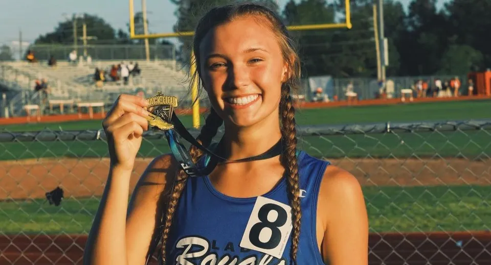 Una studentessa della Bishop J Snyder High School è in piedi con una medaglia davanti a un campo da baseball.