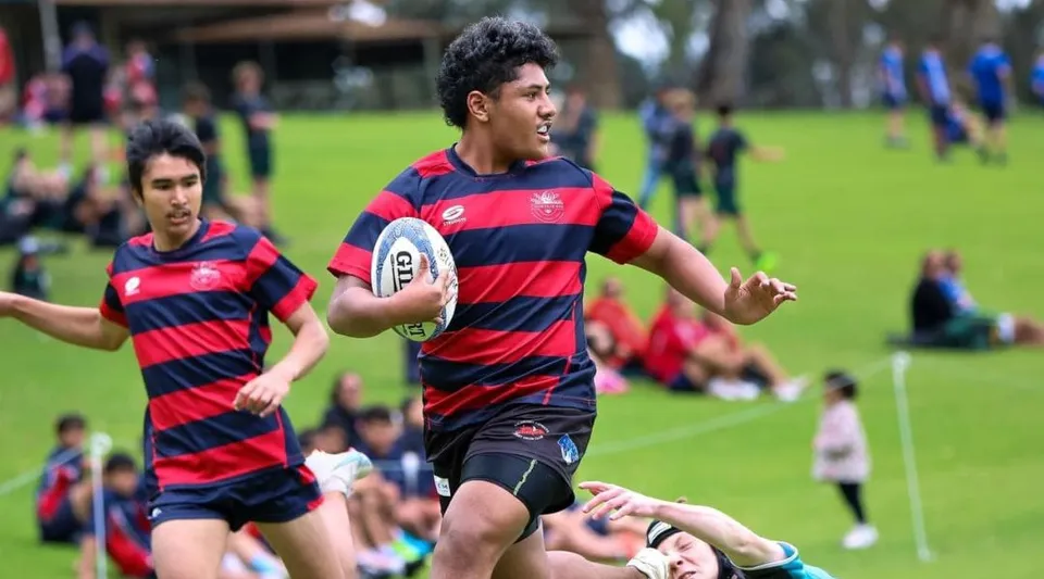 Due giocatori di rugby con una maglia a strisce corrono sul campo da gioco della Thornlie Senior High School.