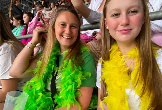 Eine Frau und ein Mädchen mit bunten Federboas auf der Tribüne eines Stadions in England