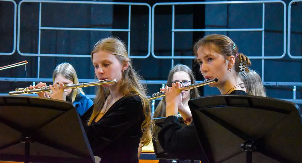 Due studentesse della Tudor Hall School suonano il flauto su un palco con uno sfondo scuro.
