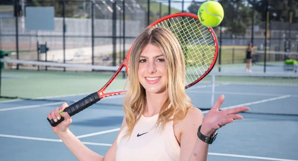 Una studentessa del San Luis Coastal Unified School District è in piedi con una racchetta da tennis su un campo da tennis.