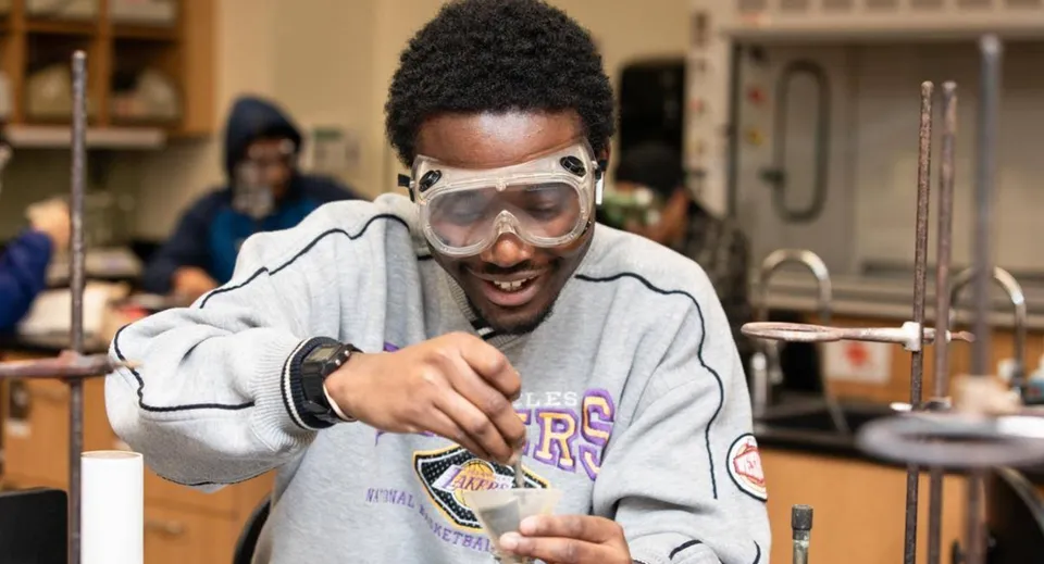 Uno studente del Milford Public School District indossa una felpa grigia e occhiali protettivi in un laboratorio.