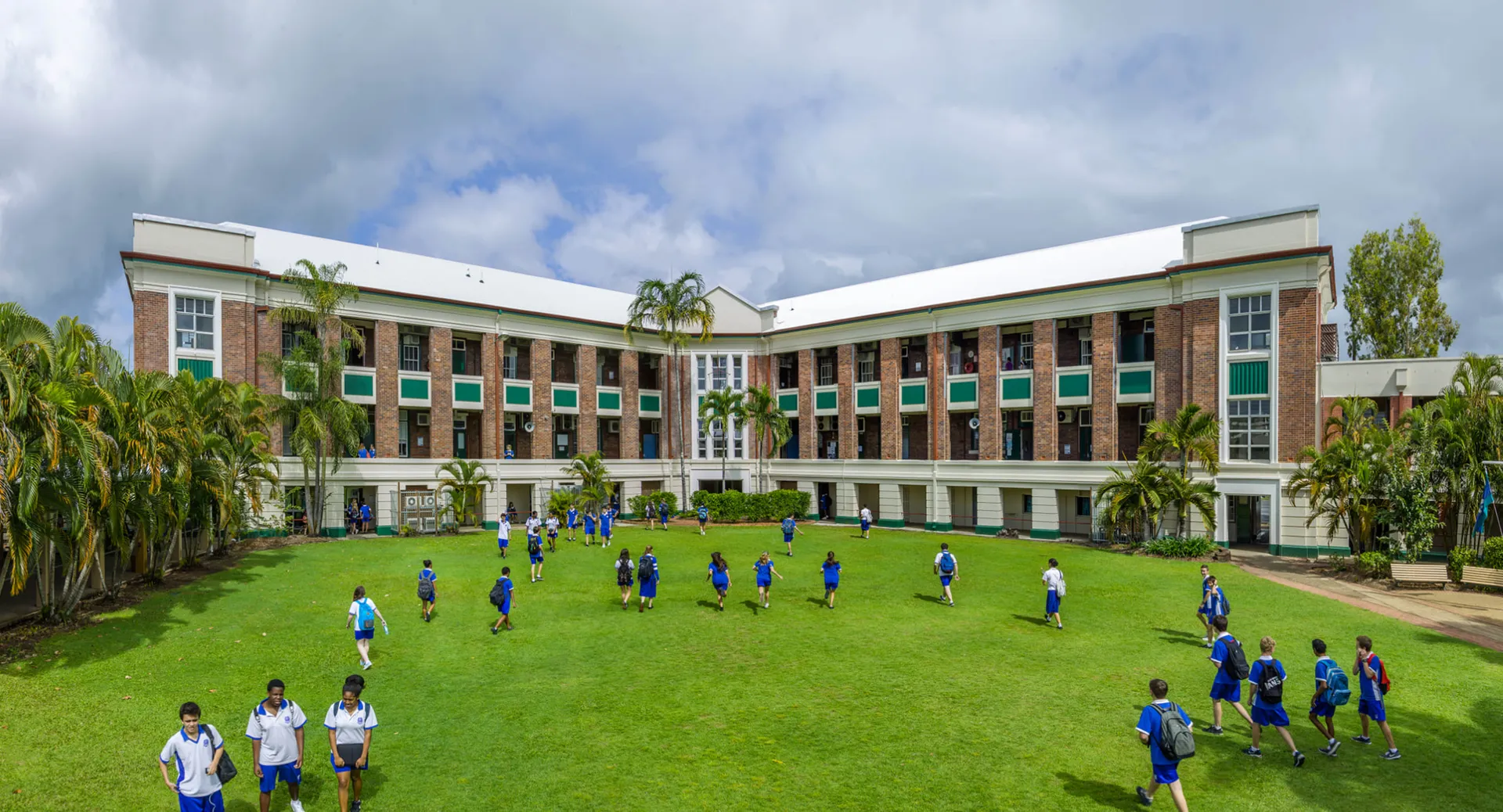 L'edificio a più piani della Cnoc Mhuire Secondary School con un prato verde e studenti e studentesse in divisa blu sul davanti.