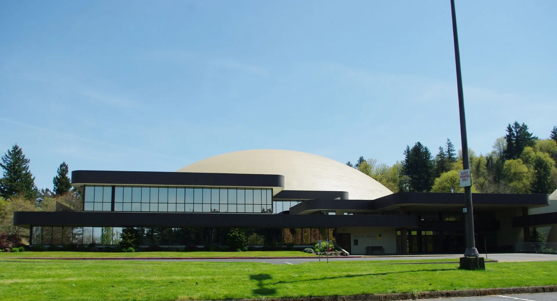 L'edificio a cupola con pareti in vetro si trova nel campus della Mannahouse Christian Academy, circondato da prati e alberi.