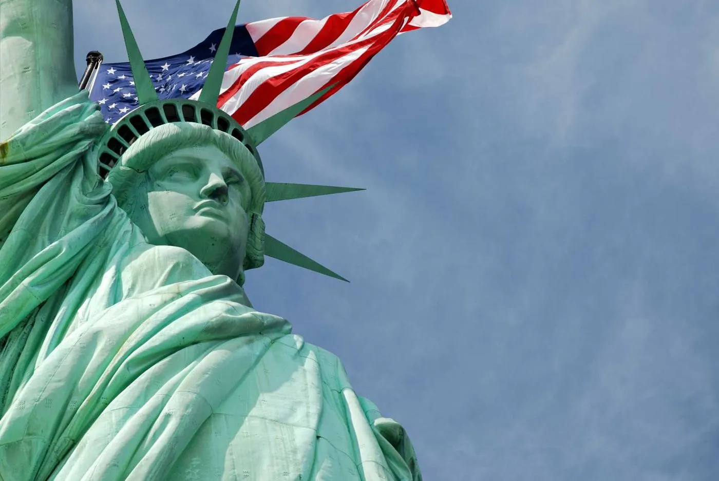 Freiheitsstatue mit US-Flagge vor blauem Himmel