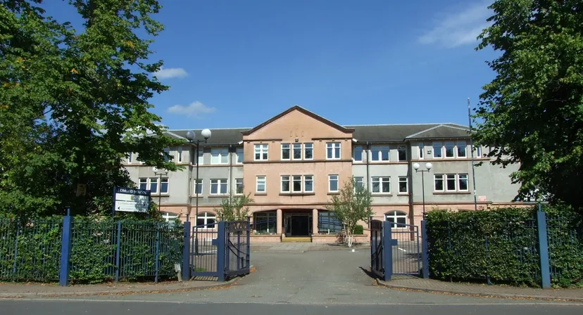 L'edificio in mattoni a più piani della Lomond School con tetto a capanna è circondato dal verde e da un viale lastricato con cancelli in primo piano.