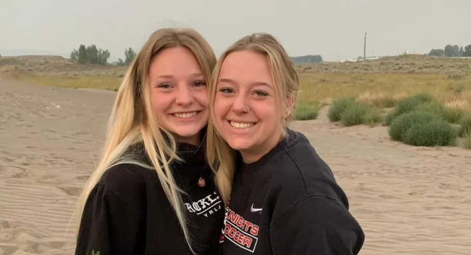 Due studentesse sorridenti in piedi nel paesaggio desertico con strade e cespugli nel campus della Hillcrest High School.