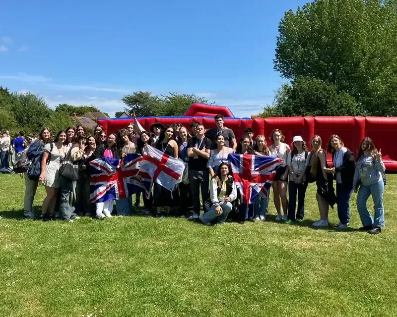 Grupo numeroso de alumnos con banderas del Reino Unido e Inglaterra ante un circuito hinchable