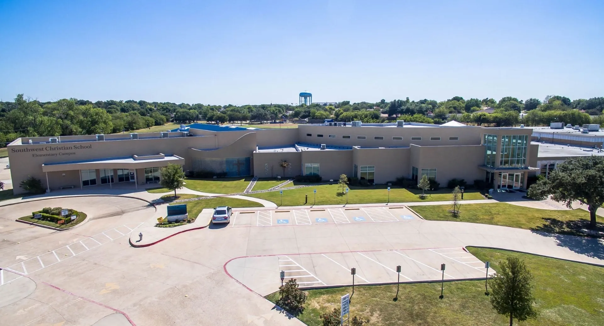 L'edificio principale moderno della Southwest Christian Academy con torre dell'acqua e area verde circostante con sentieri.