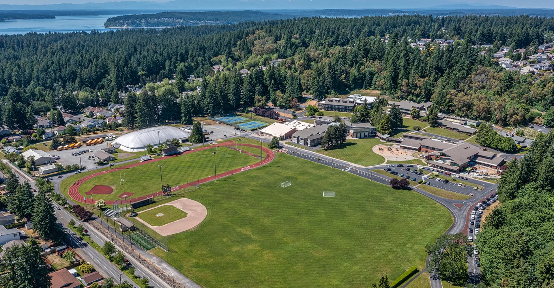 L'ampio centro sportivo della Charles Wright Academy è immerso in un paesaggio boschivo con un campo da baseball e altre strutture sportive.