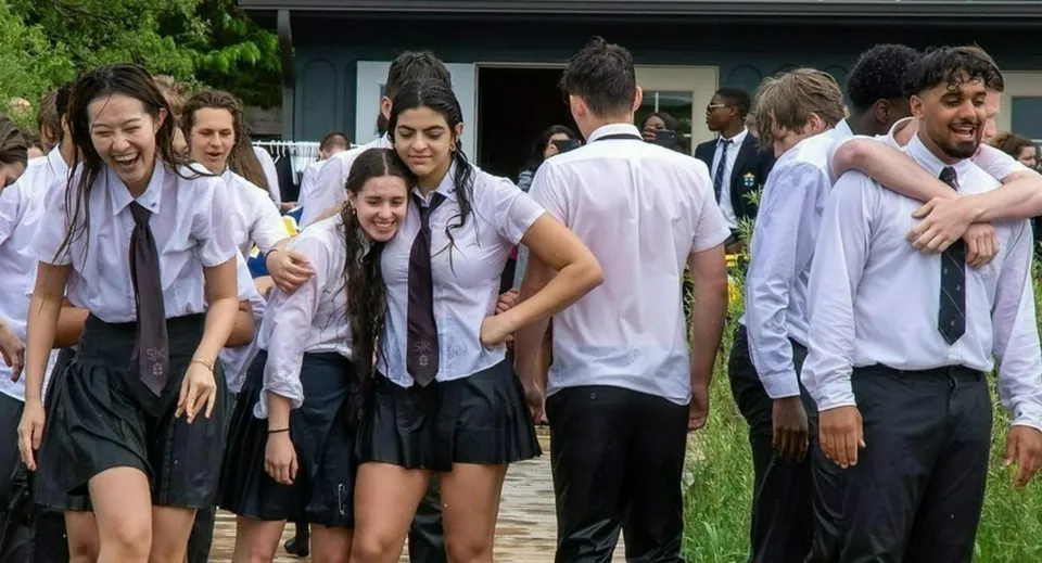 Un gruppo di studenti e studentesse si trova all'aperto davanti a un edificio del campus della St. John’s-Kilmarnock School.