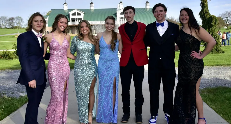 Un gruppo di persone vestite elegantemente sta davanti all'edificio storico nel campus del St. Andrew's College.