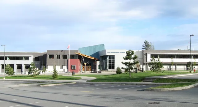 Das moderne Schulgebäude der Panorama Ridge Secondary School mit Rasenfläche und Parkplatz im Vordergrund.