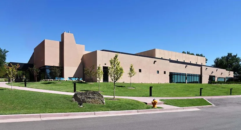 L'edificio moderno a più piani della Fountain Valley School of Colorado sorge su un prato ben curato con alberi e cielo azzurro.
