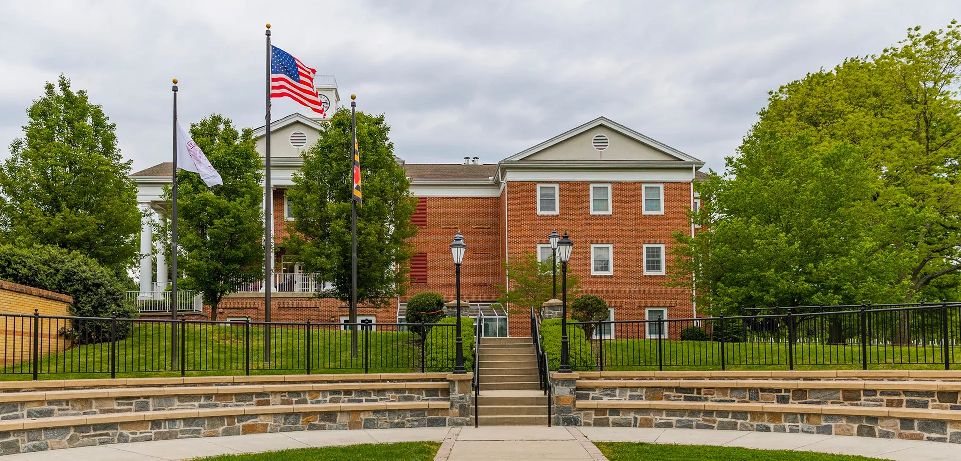 L'edificio in mattoni della West Nottingham Academy con bandiera americana e sentiero adiacente circondato da aree verdi.