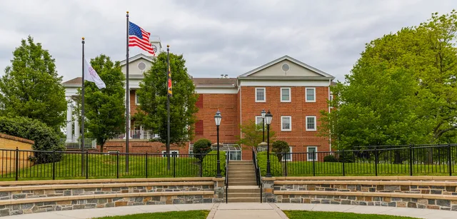 L'edificio in mattoni della West Nottingham Academy con bandiera americana e sentiero adiacente circondato da aree verdi.